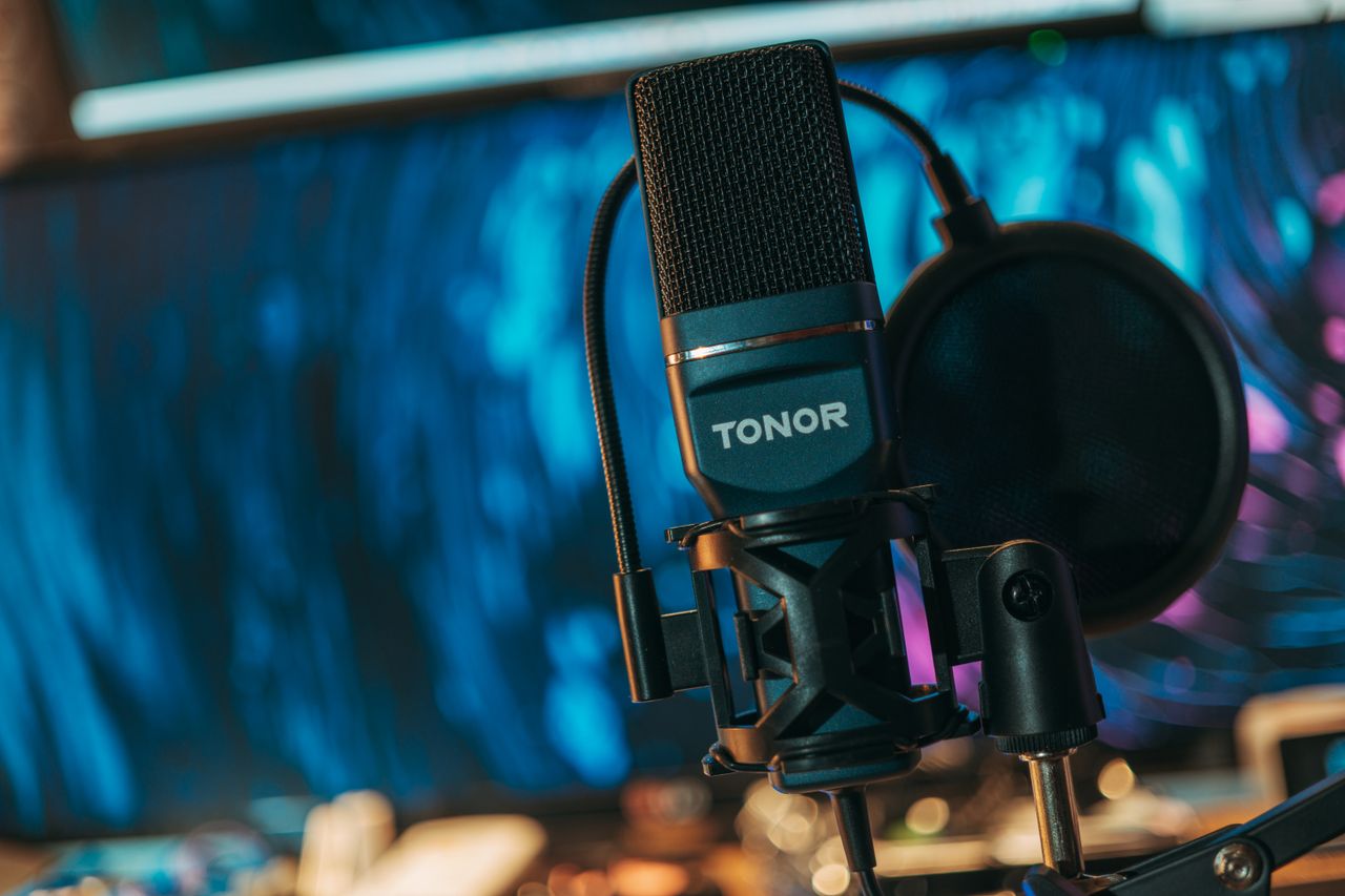 Close-up of a Tonor microphone with pop filter in a music recording studio.